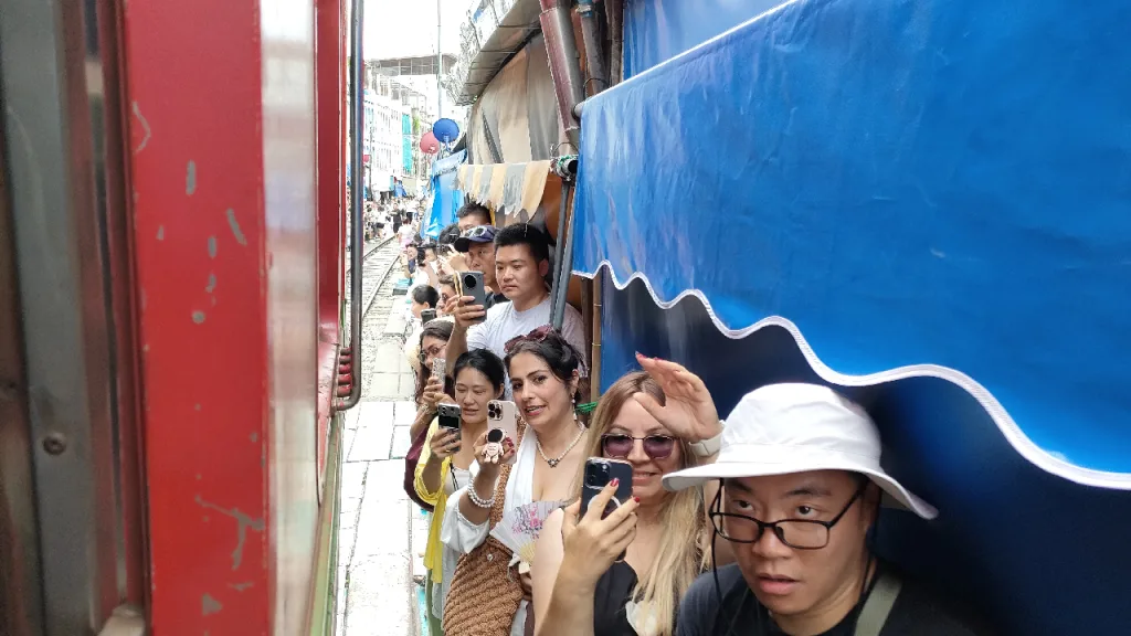 メークロン市場を進むメークロン線の列車とそれを見る観光客